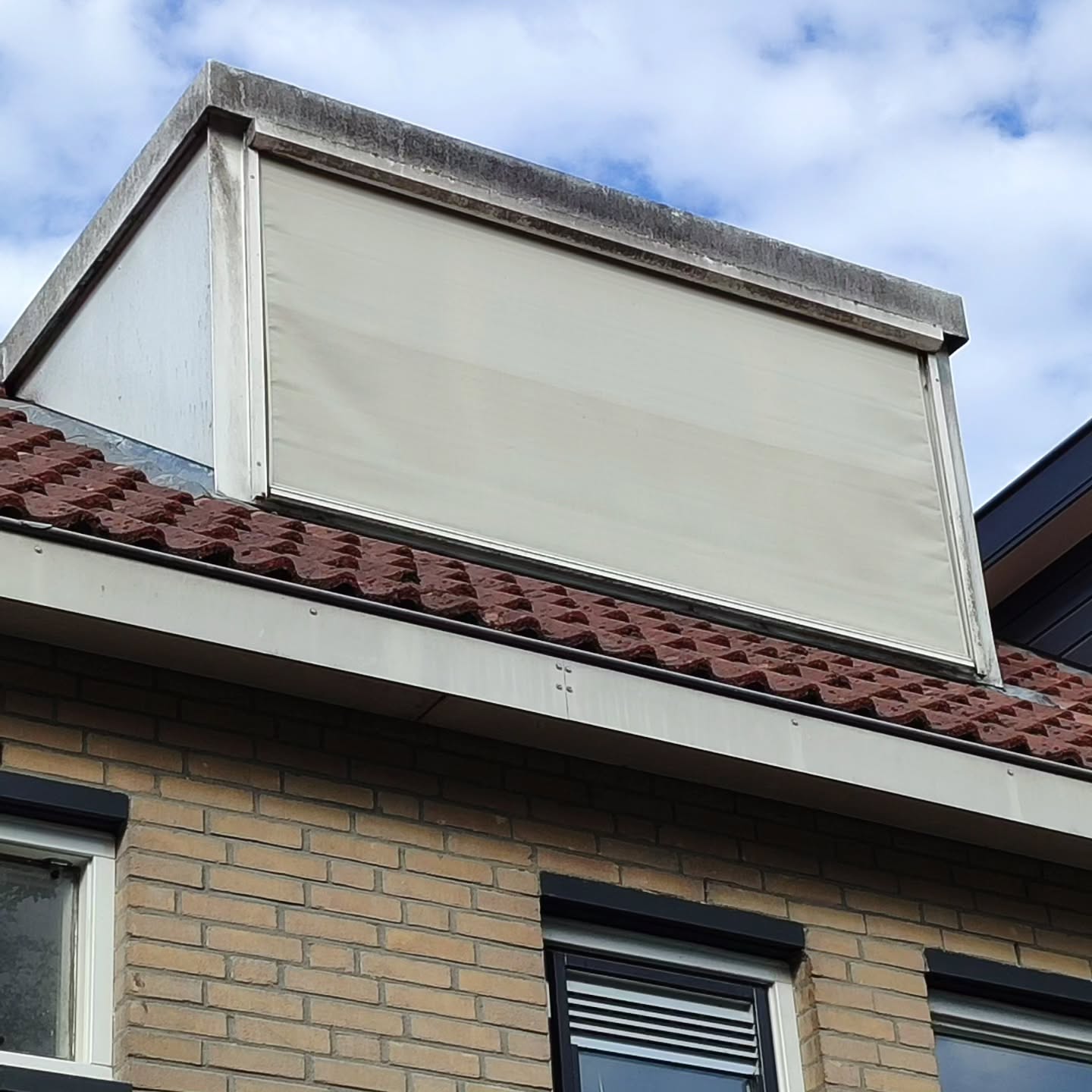 Een grijs uitgeslagen dakkapel met zonnescherm voor de reiniging